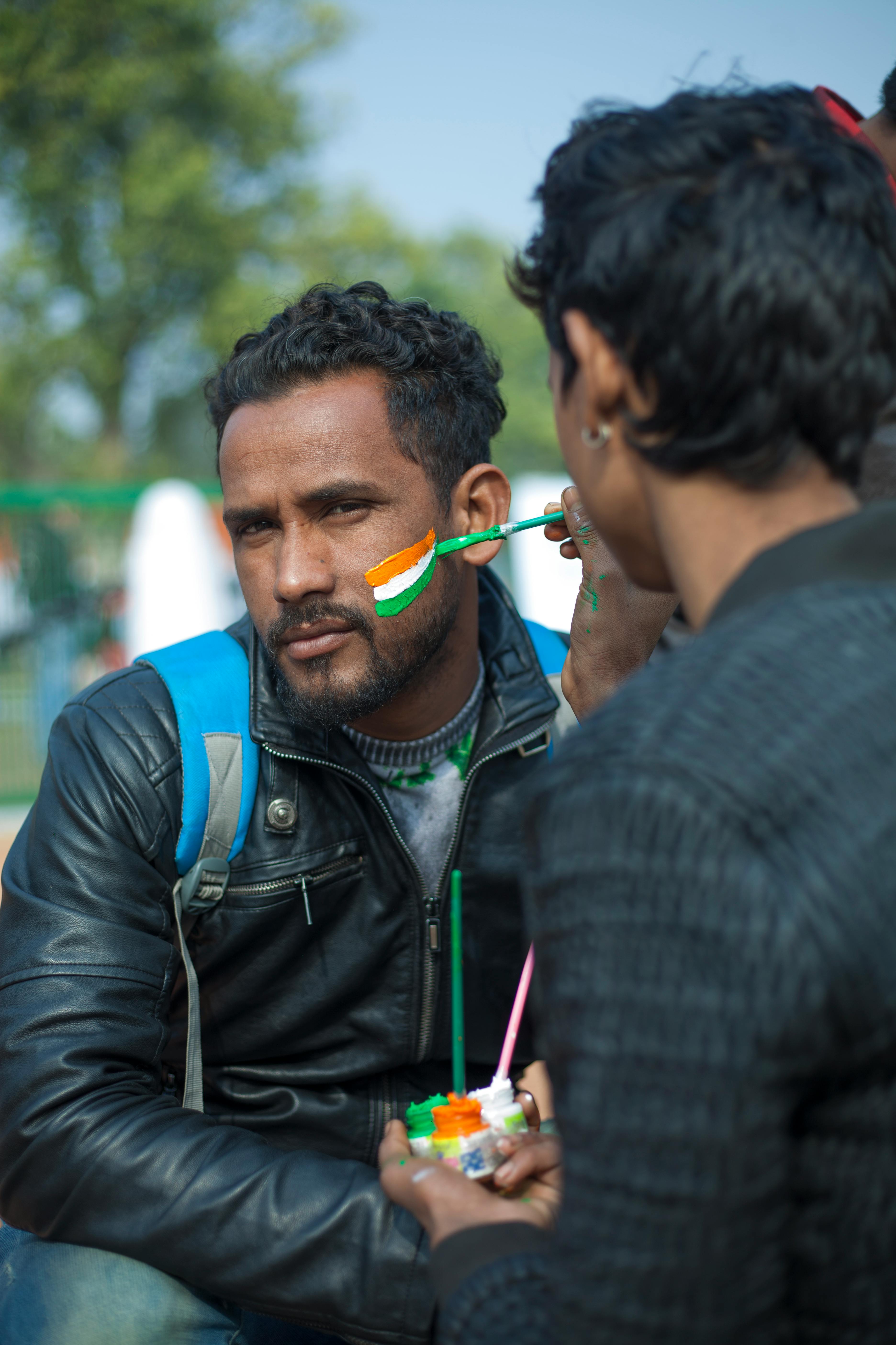 Man getting face painted with Indian flag colors during Republic Day in Delhi, India.