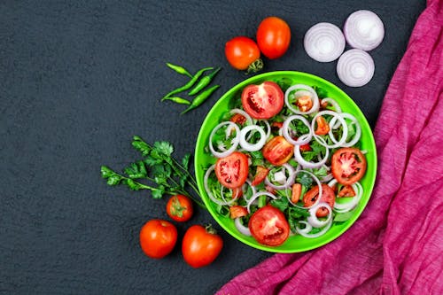 Close-Up Shot of a Vegetable Salad on a Plate beside Tomatoes and Chilli Peppers