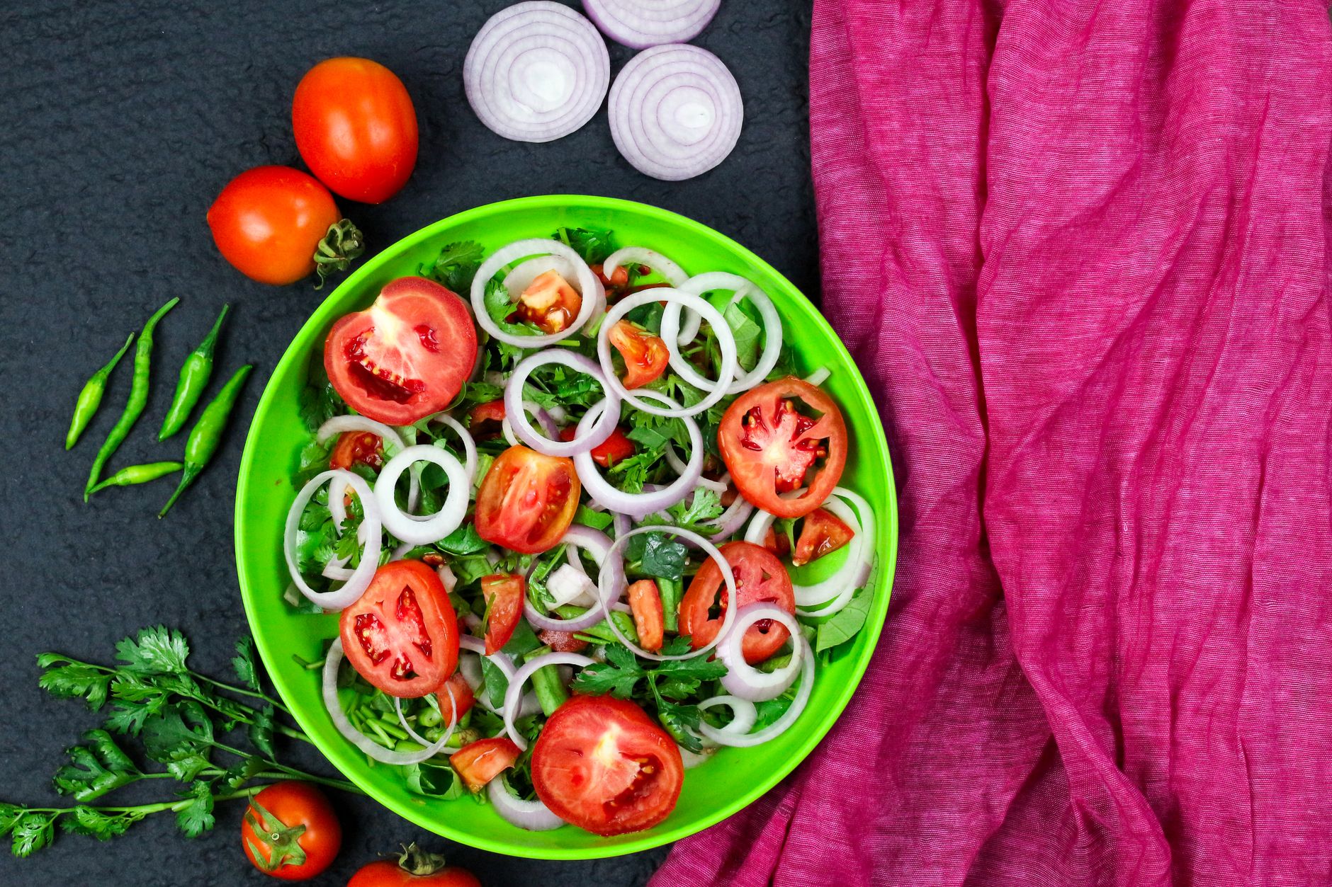 健康飲食不無味:5道簡單美味食譜 Vibrant vegetable salad on a green plate with chili, tomatoes, and onions, perfect for a healthy diet.
