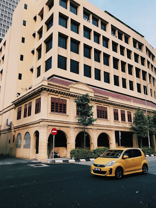 A Yellow Car on the Road Near the Building