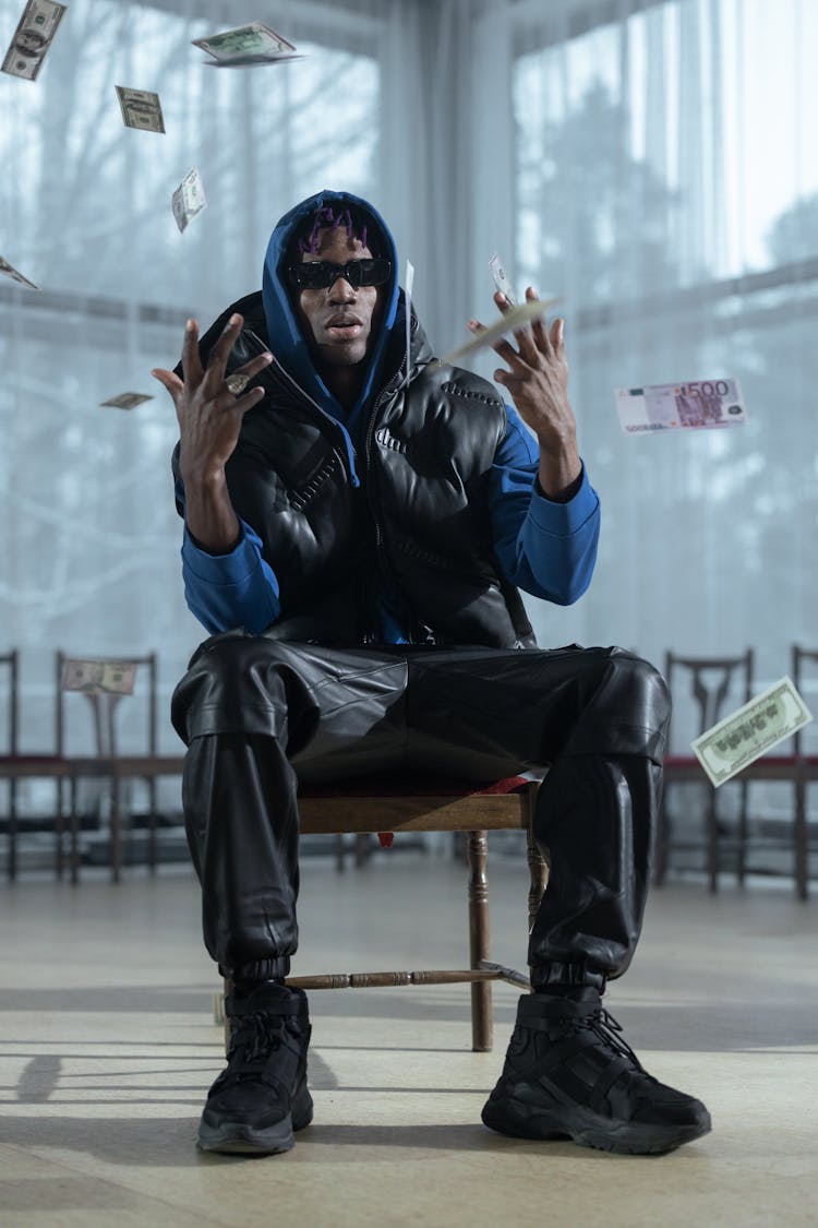 Fashionable Man Sitting On A Chair And Throwing Money In The Air 