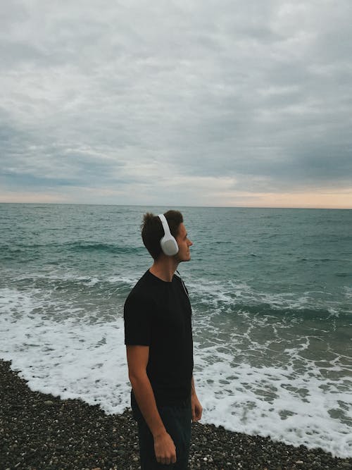 A Man Wearing Wireless Headphones at the Beach