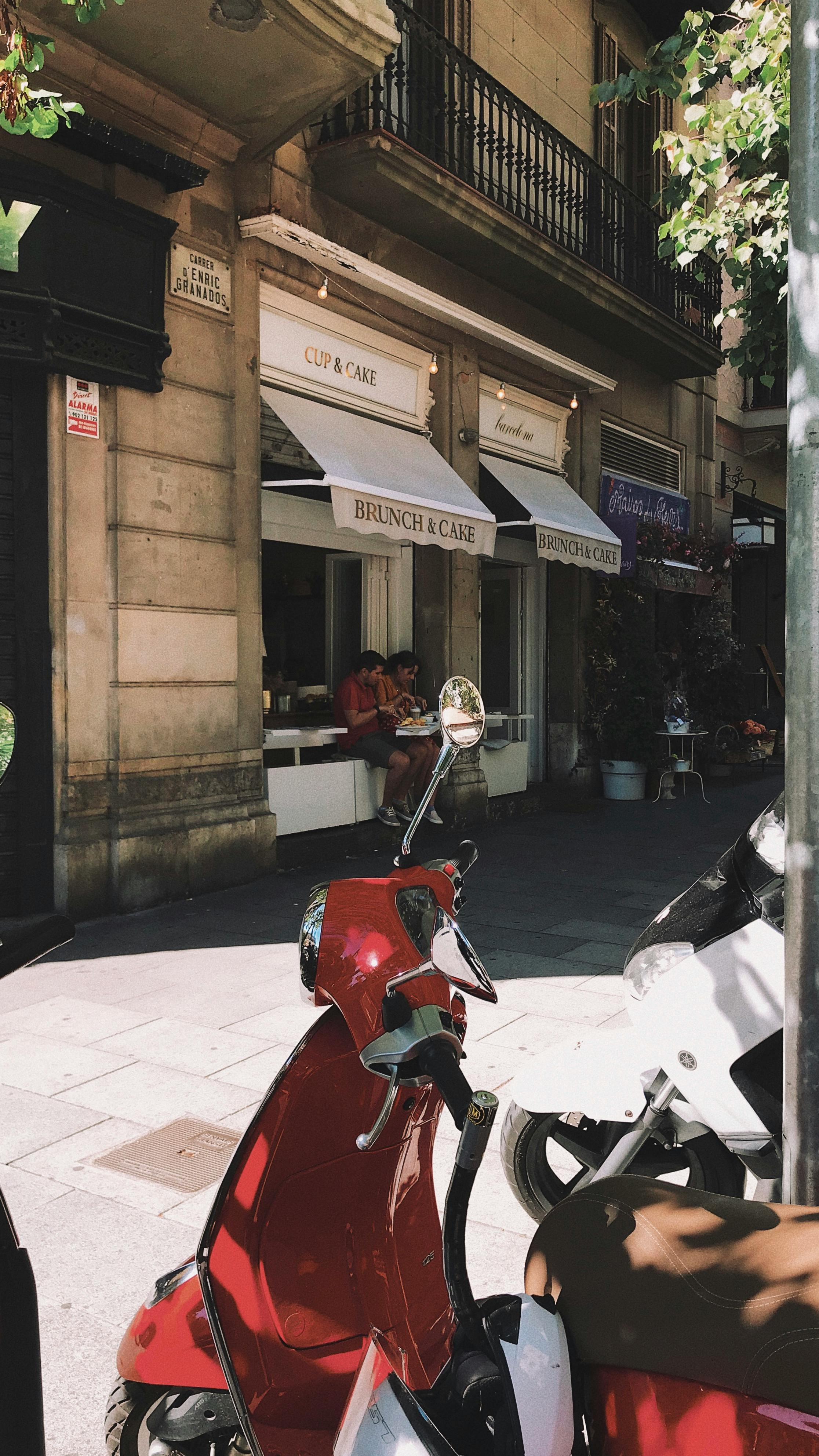 a red scooter parked beside a brown building