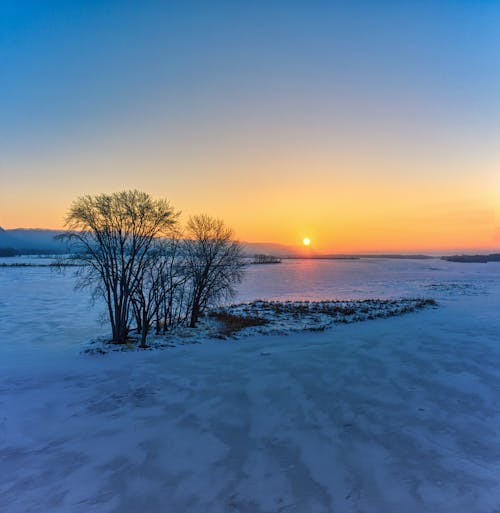 Aerial View of a Field Covered in Snow at Sunset