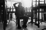 Black and white portrait of an African American man sitting in a closed restaurant.