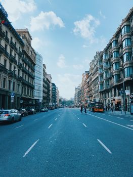 Discover a lively urban street in Barcelona, showcasing historical architecture and bustling city life.