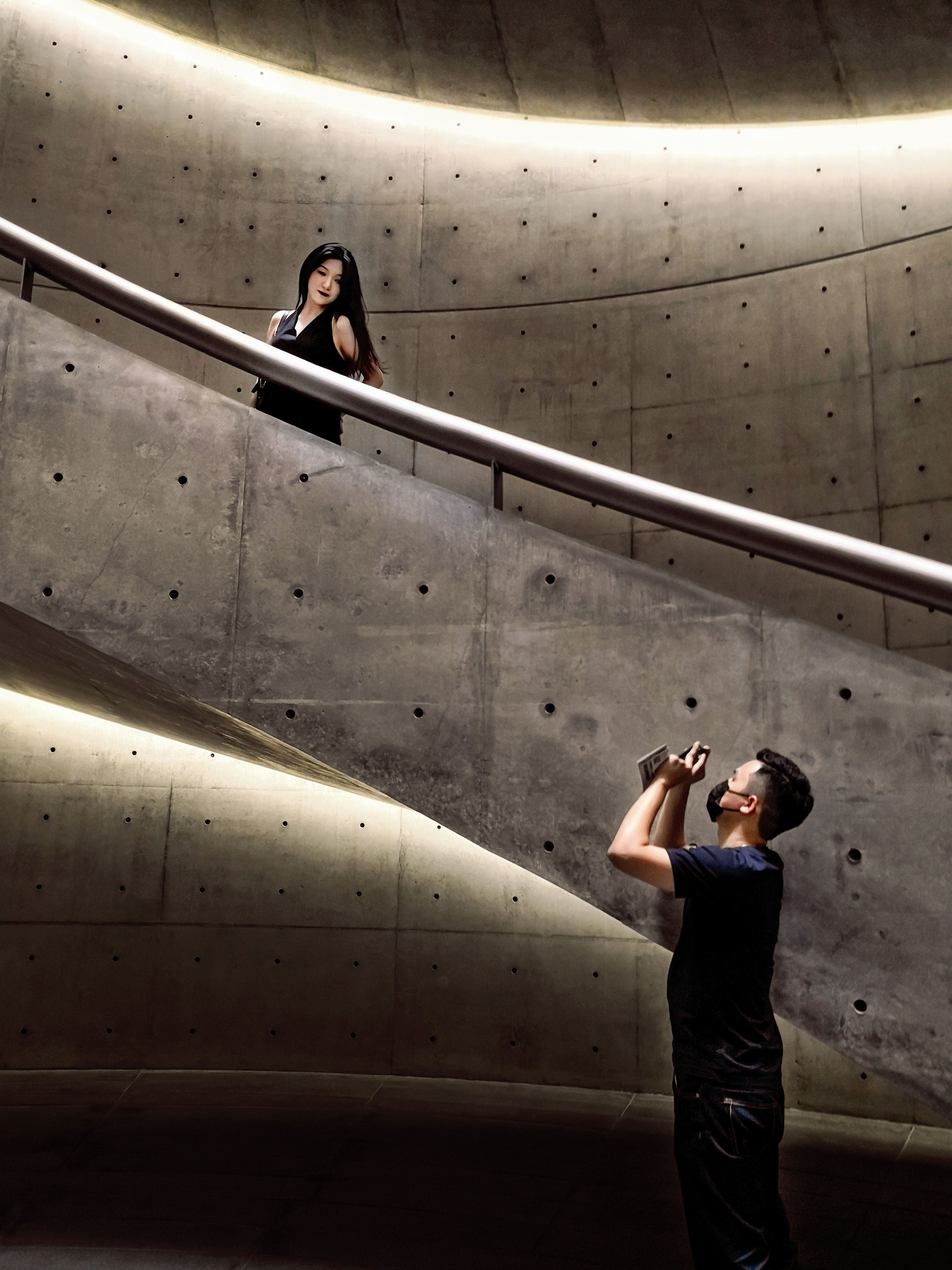 Man Taking a Picture of Woman in Black Dress Standing on Concrete ...