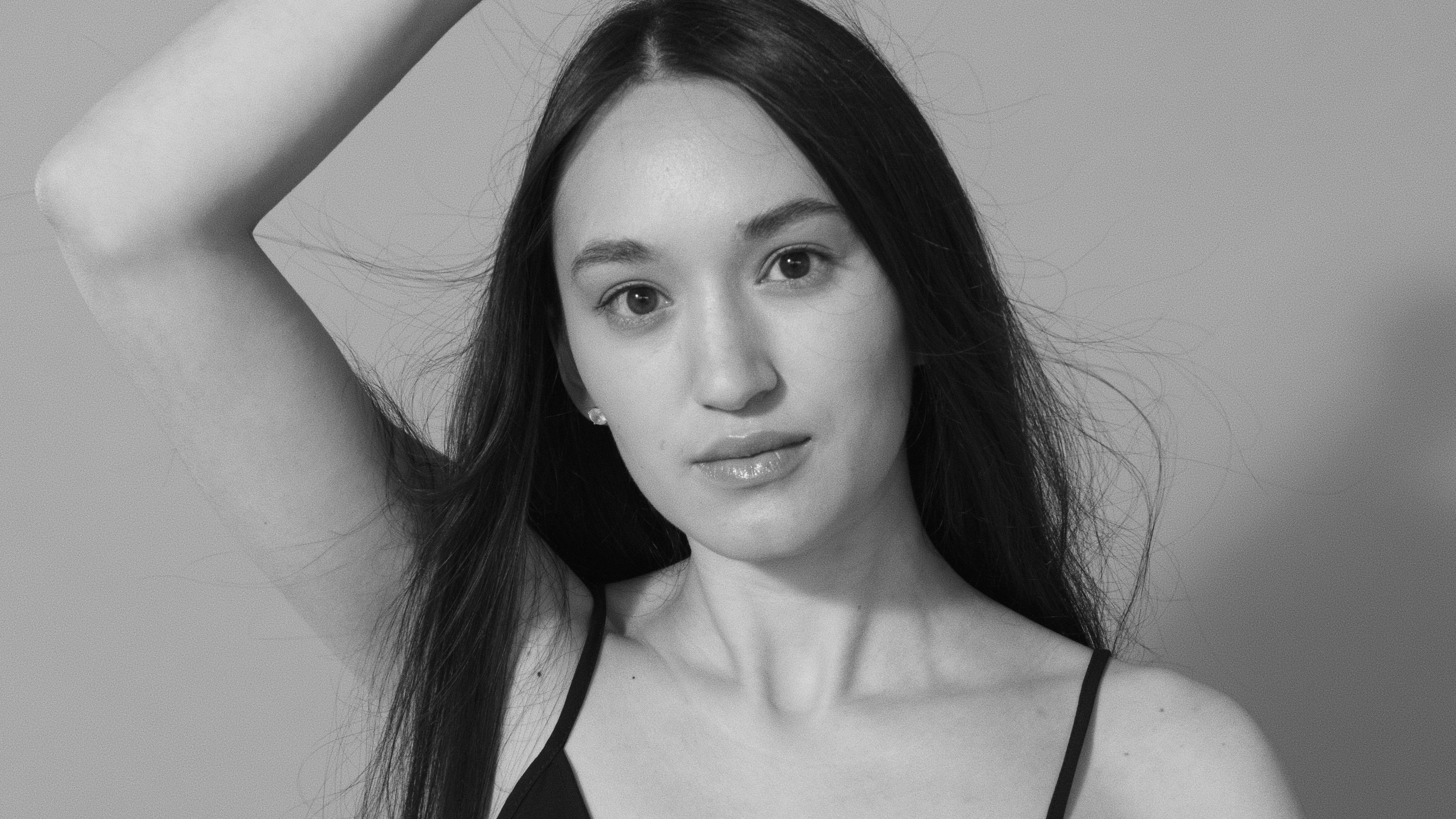 Black and white portrait of a woman with long hair, striking a pose.