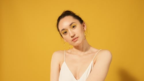 Close-Up Photo of a Woman with Yellow Eyeshadow Makeup Looking at the Camera