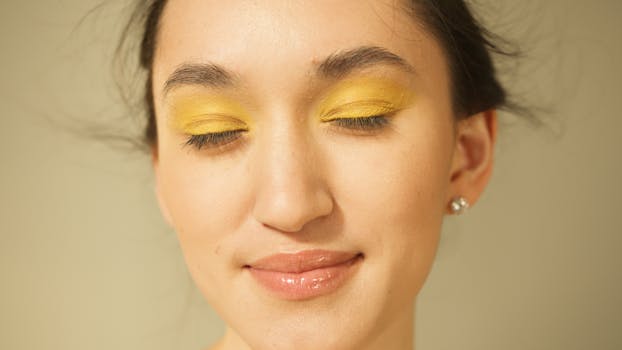 A serene close-up portrait of a woman with vibrant yellow eyeshadow and a gentle smile.
