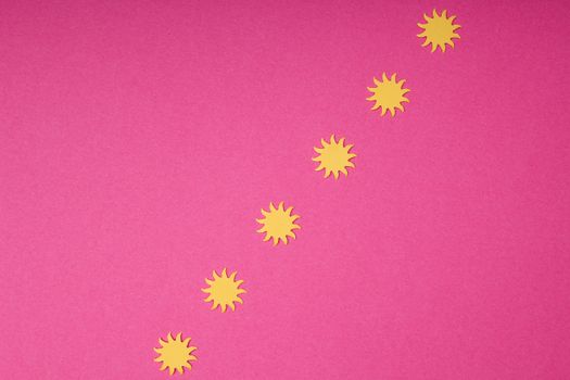 Creative arrangement of yellow sun shapes on a bold pink background, ideal for summer-themed designs.