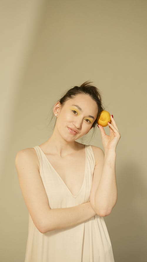 Woman in a Beige Top Holding a Fruit