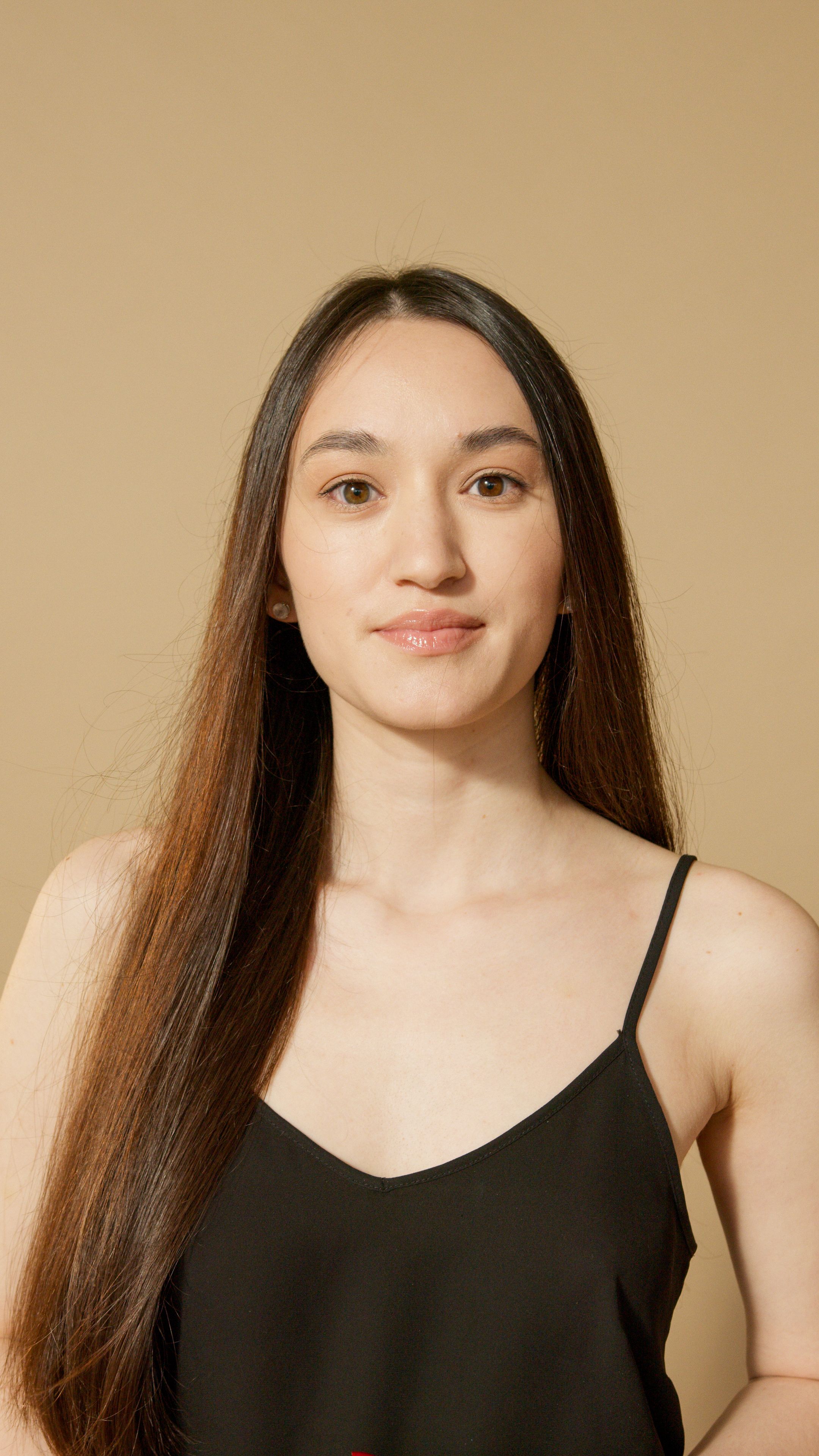 Sophisticated studio portrait of a young adult woman with long hair, exuding confidence and grace.