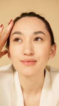 Close-up portrait of a woman with red nails and pearl earrings, looking thoughtful.