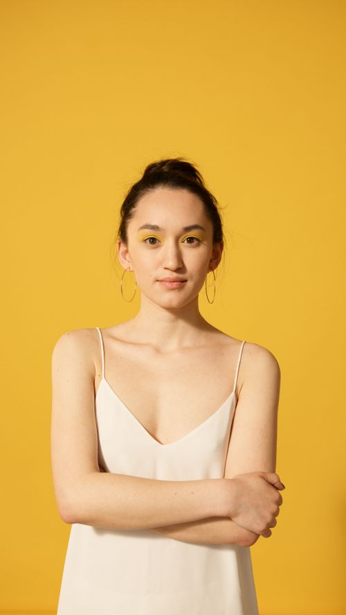 Free Stunning portrait of a woman posing confidently against a vibrant yellow backdrop. Stock Photo