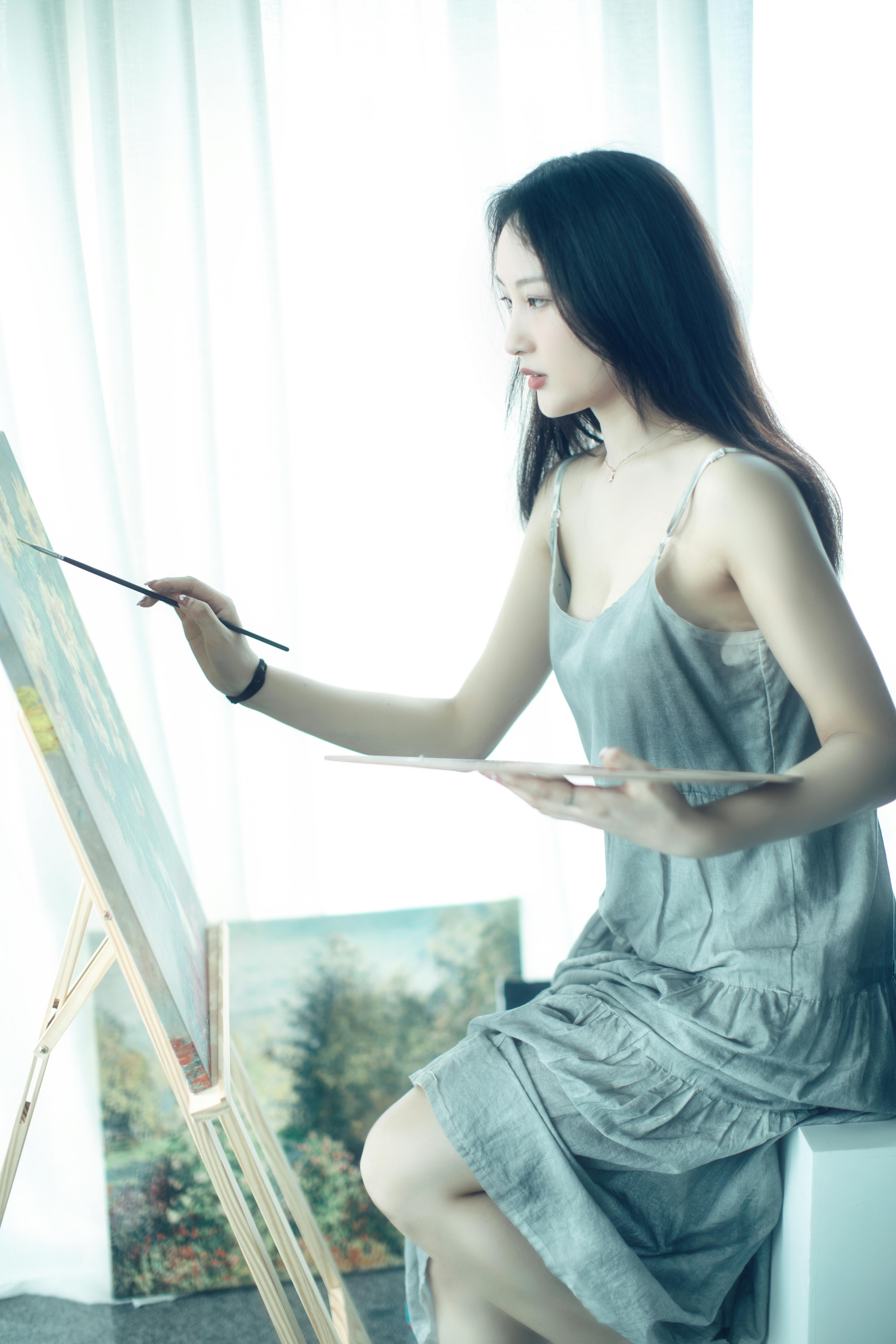 A serene portrait of a woman artist painting on a canvas in a bright, creative studio.