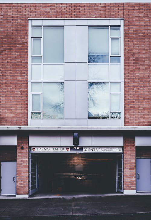 Exterior of brick building with entrance of indoor parking located in city in daylight