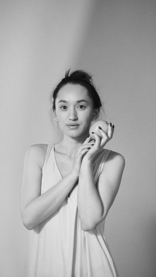 Free Monochrome portrait of a young adult woman holding a fruit, showcasing elegance and simplicity. Stock Photo