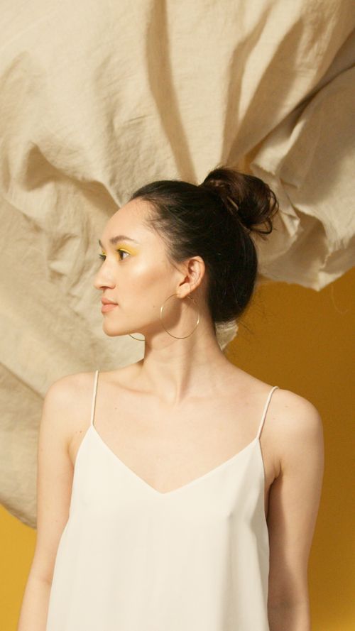 Free Portrait of a woman posing with a dynamic fabric backdrop, showcasing elegance and simplicity. Stock Photo