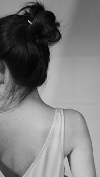 Stylish monochrome portrait capturing a woman's back and hair bun, exuding elegance.