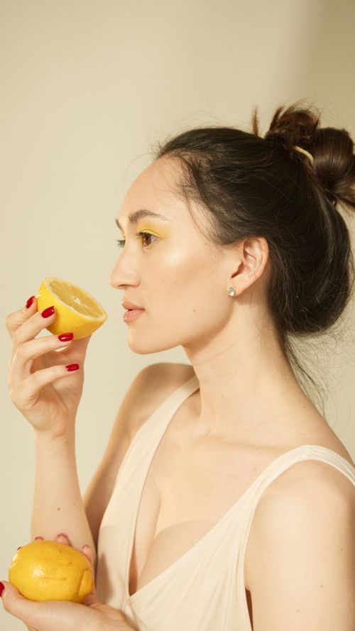 Free Profile view of a woman holding lemons, showcasing beauty and freshness with soft lighting. Stock Photo