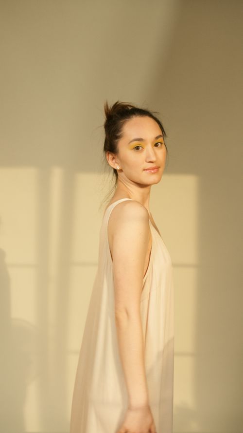 Free Portrait of a woman in a beige dress with natural sunlight casting soft shadows. Stock Photo