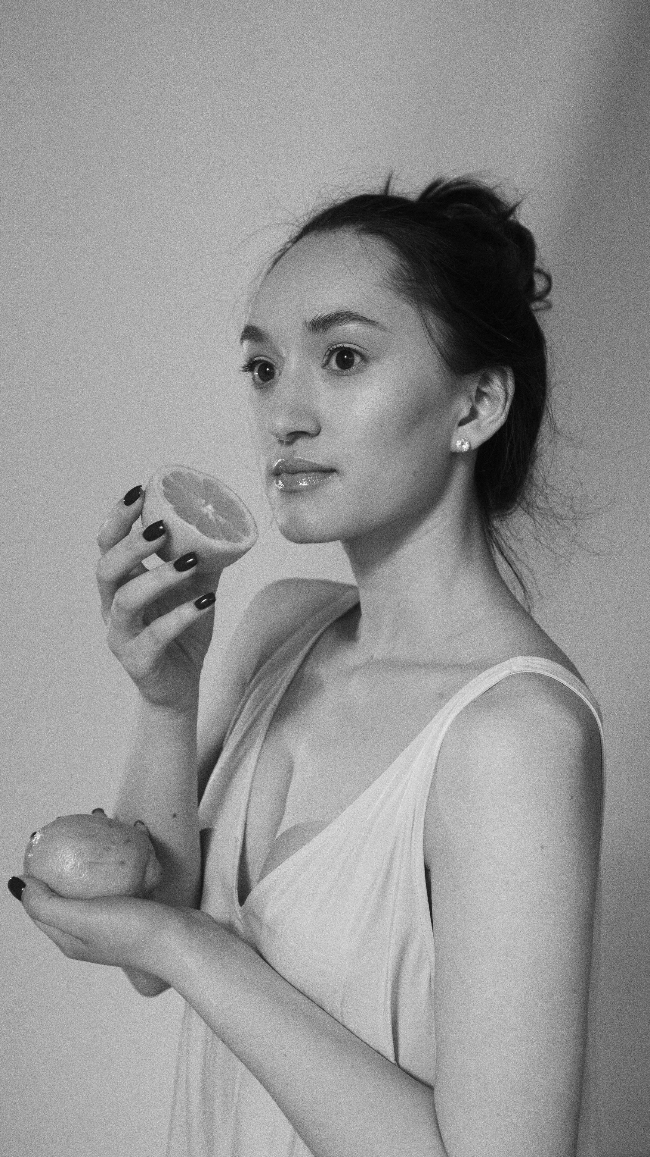 Artistic black and white portrait of a woman holding a lemon slice.