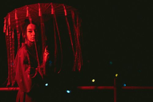 Free Artistic portrait of a woman in a kimono under an umbrella, highlighted by red light. Stock Photo