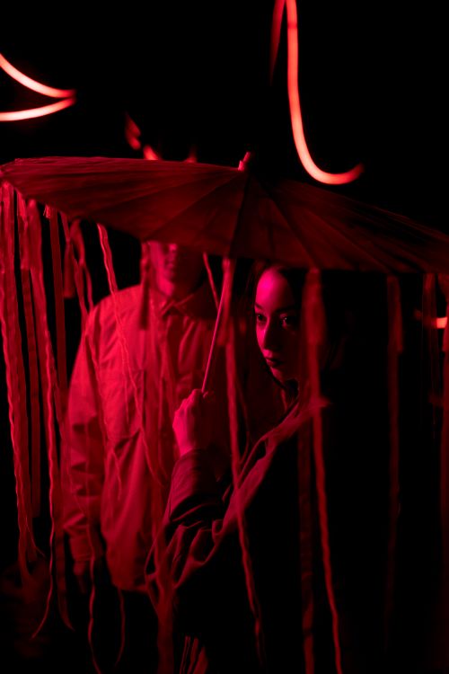 Free A couple in traditional Japanese attire under a red-lit umbrella, evoking mystery. Stock Photo