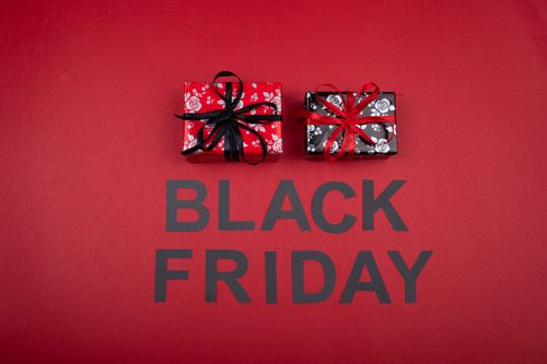 Free Festive Black Friday promotion with gift boxes on a vibrant red background. Stock Photo