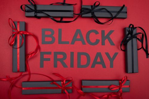 Free Black Friday themed image with gift boxes and ribbons on a red background. Stock Photo