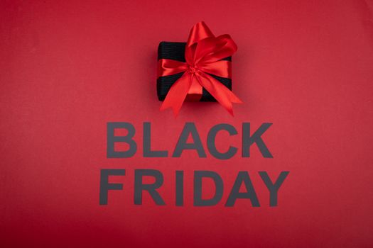 Black gift box with red ribbon, perfect for Black Friday sales promotions.