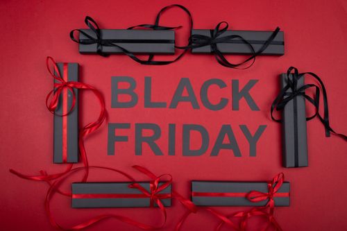 Free Black Friday themed gift boxes with red and black ribbons on a bold red backdrop. Stock Photo