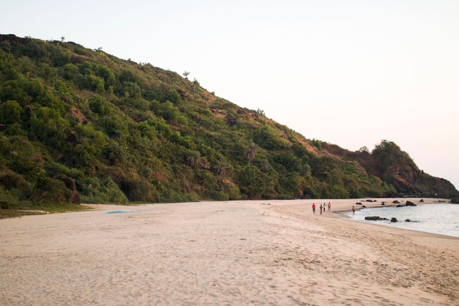 Peaceful tropical beach with gentle waves and verdant hills, perfect for a serene getaway.