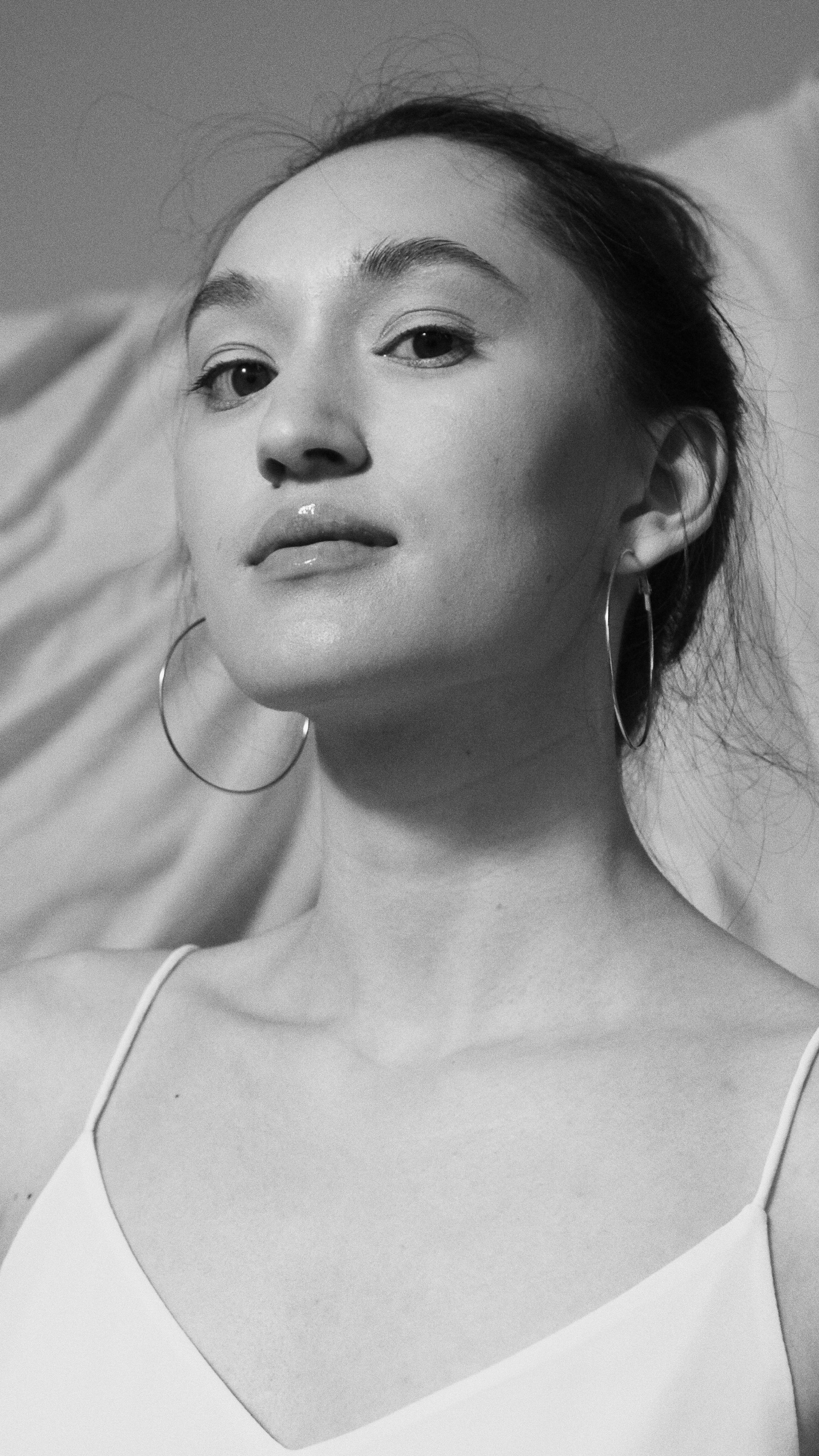 Striking black and white portrait of a woman with hoop earrings in a studio setting.