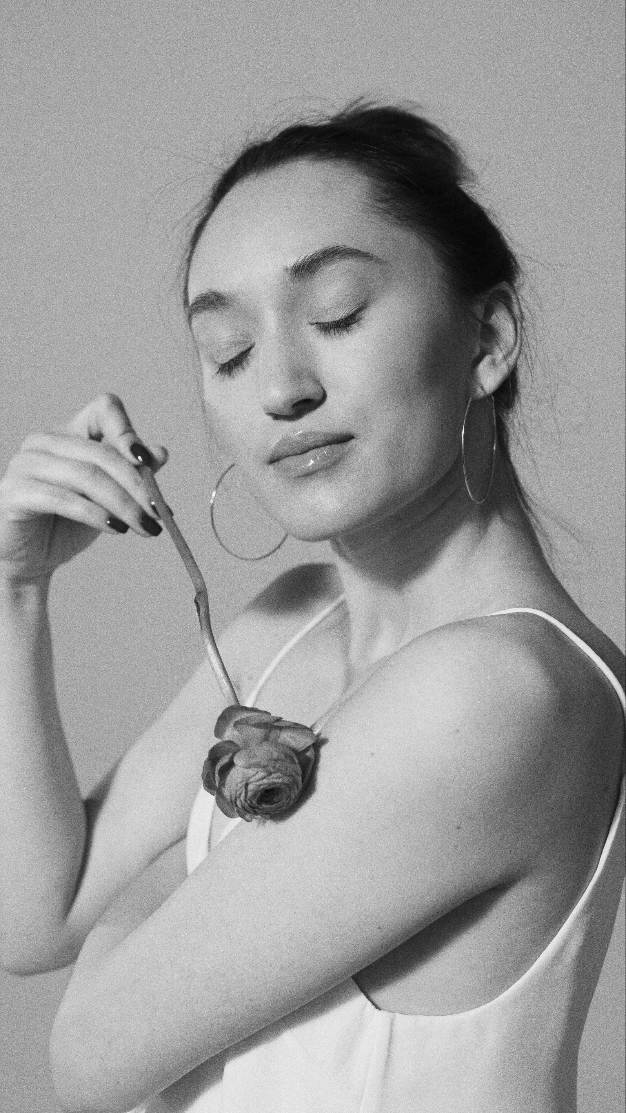 A monochrome portrait of a woman holding a rose, conveying elegance and calm.