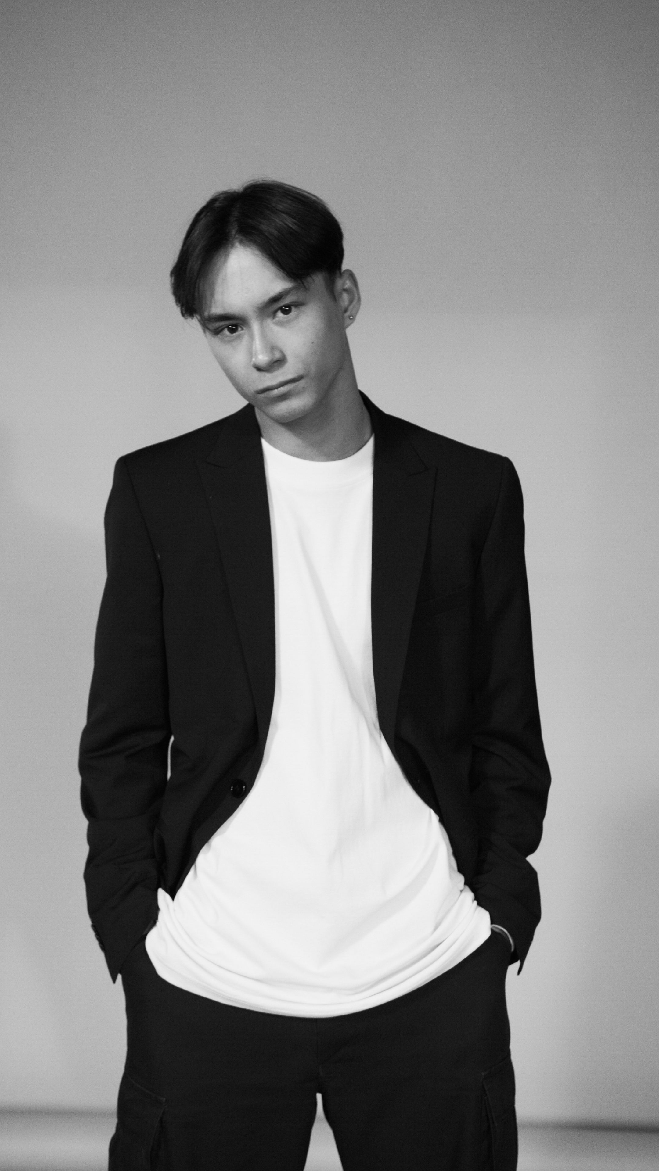 Portrait of a stylish Asian man in a blazer, hands in pockets, monochrome.