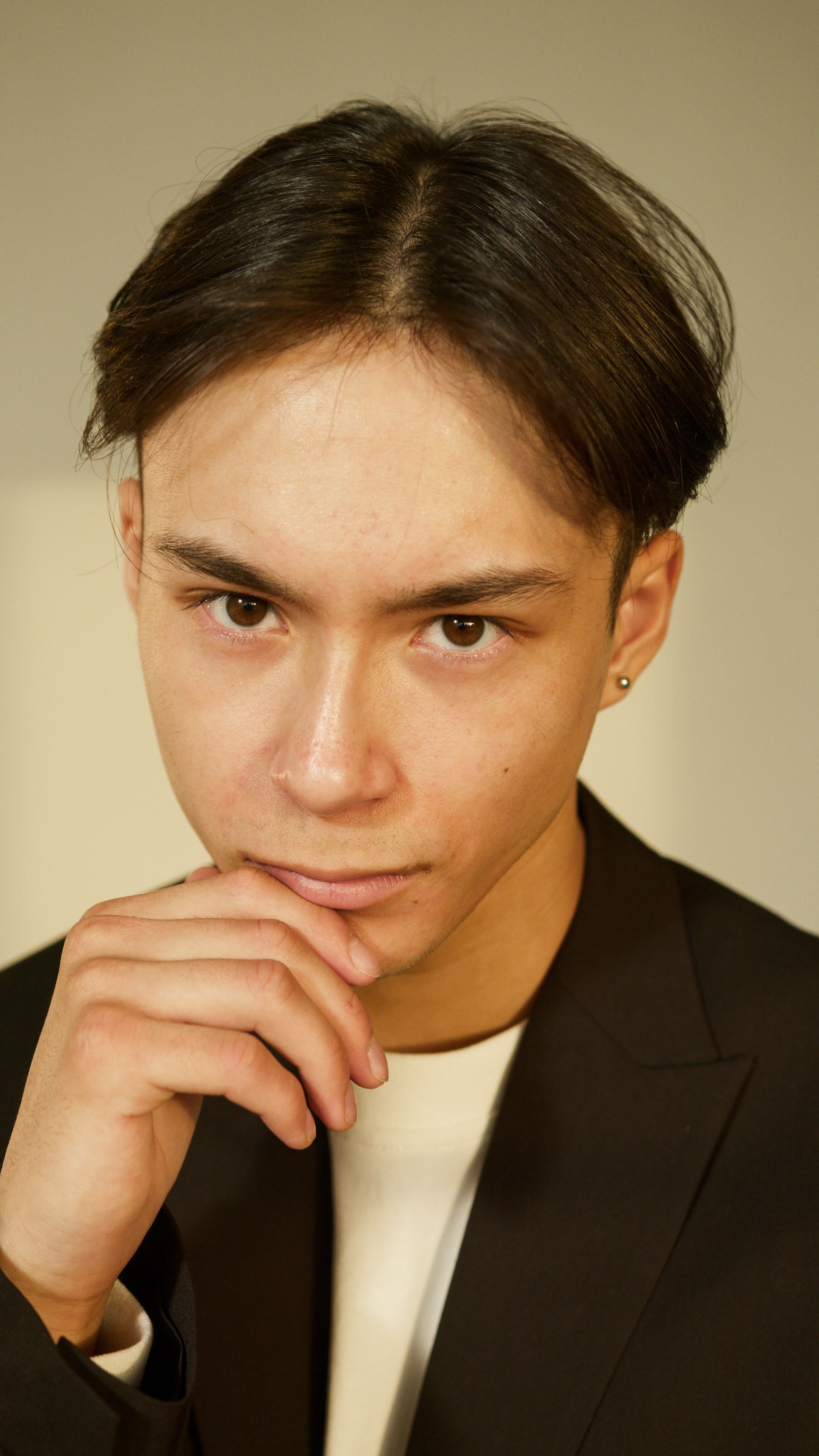 Close-up portrait of a young man with contemplative expression indoors.
