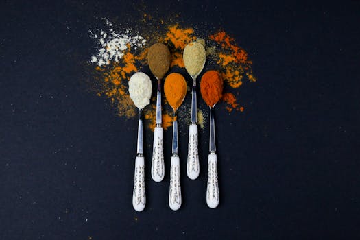 Top view of assorted spices on decorative spoons placed on a dark background for culinary inspiration.