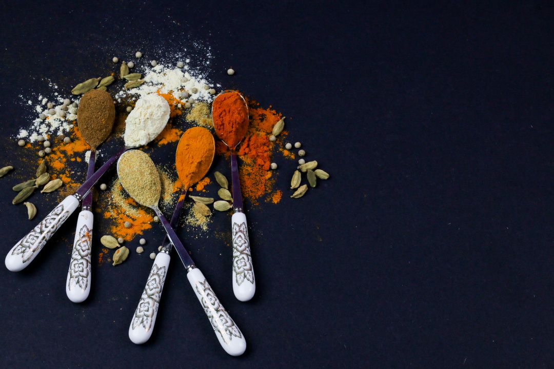 Gujarat's Vegetarian Food Heritage: Why It Leads India 3 Assorted Indian spices including cumin, turmeric, and chilli powder on decorated spoons against a dark background
