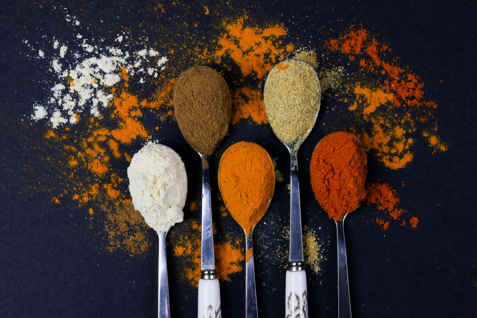 Small glass shot cup filled with golden ginger turmeric shot on wooden surface
