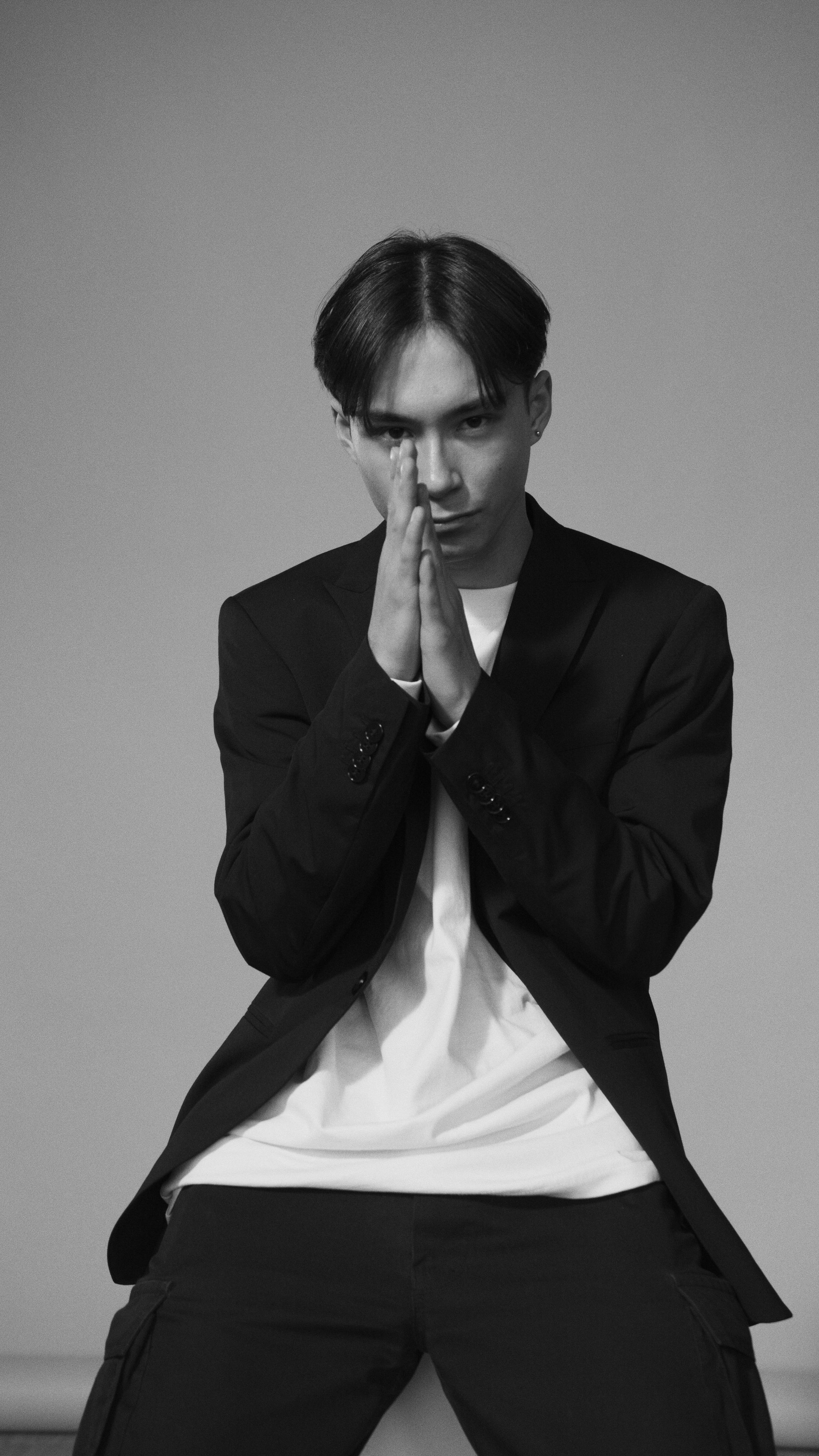 Monochrome portrait of an Asian man in a black blazer with a thoughtful pose.