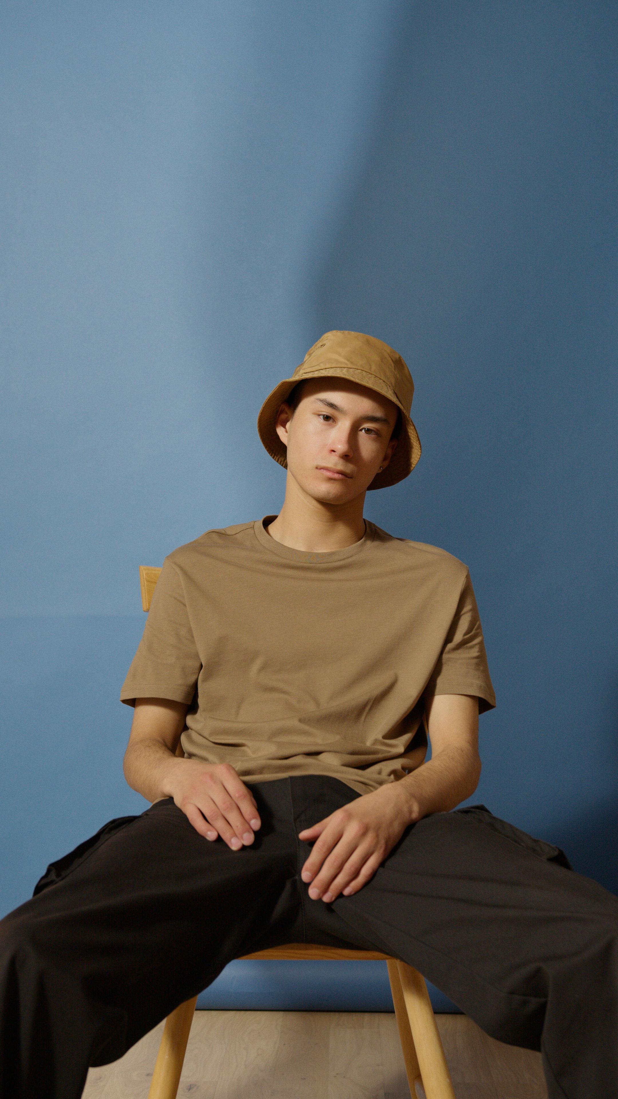 A Man Wearing a Brown Shirt and a Bucket Hat Sitting on a Chair · Free ...