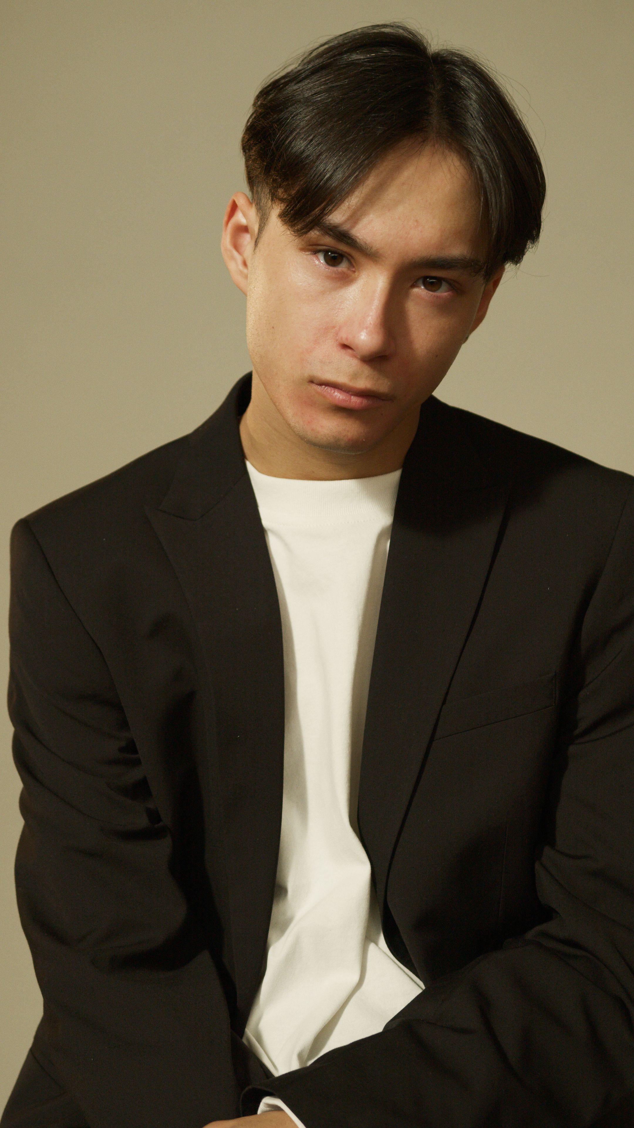 Asian man in a black blazer with a serious expression, looking at the camera.