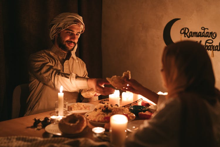 Man And Woman In Headscarves Eating At A Table Decorated For Ramadan