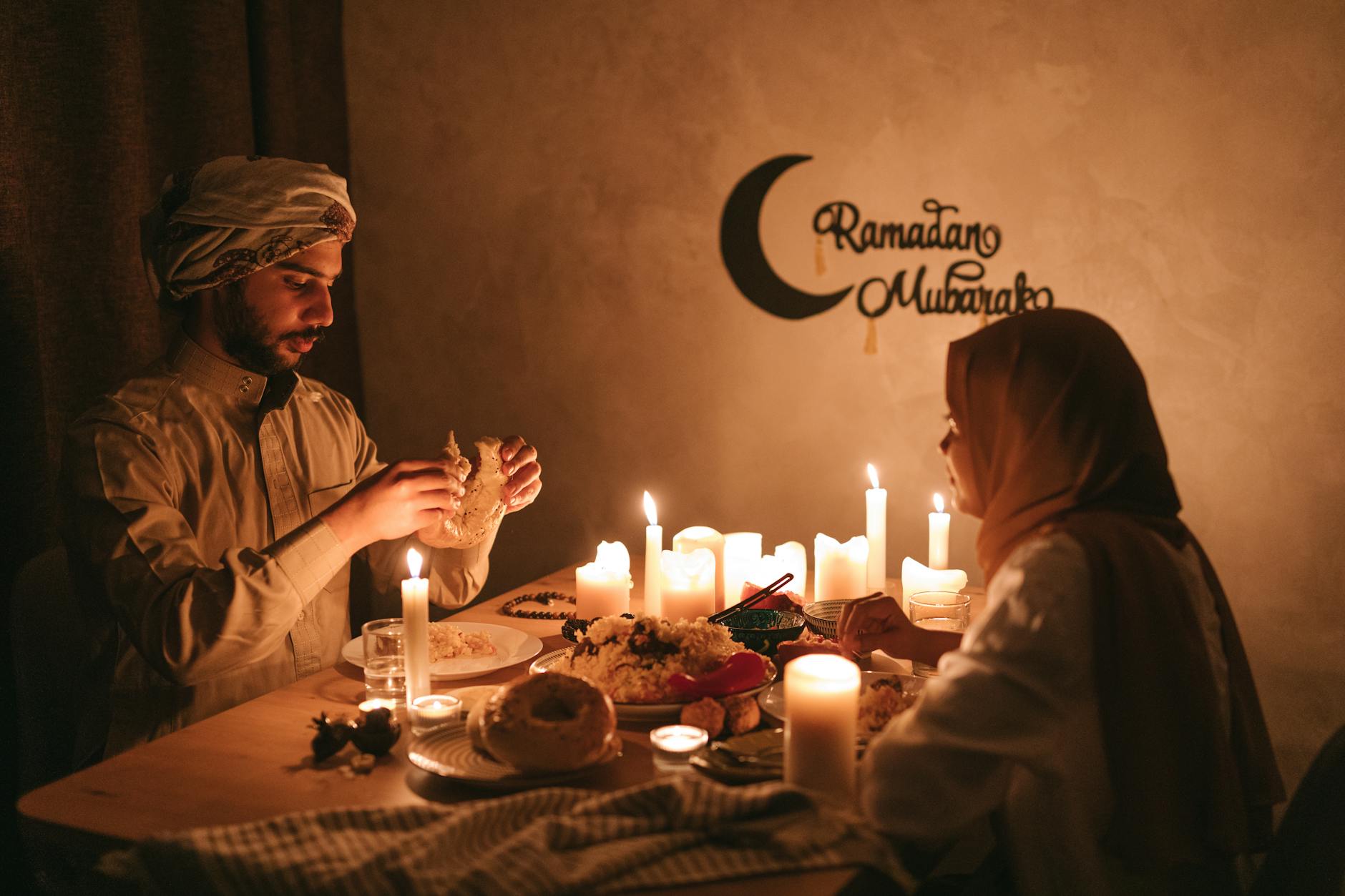 A man and woman share a traditional Ramadan meal by candlelight, symbolizing cultural and religious significance.