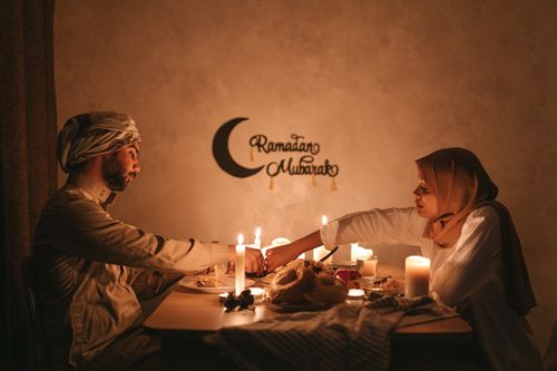 Free Couple enjoying iftar meal during Ramadan by candlelight, creating a warm and serene ambiance. Stock Photo