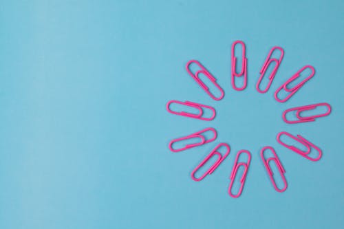 
Pink Paper Clips on a Blue Surface