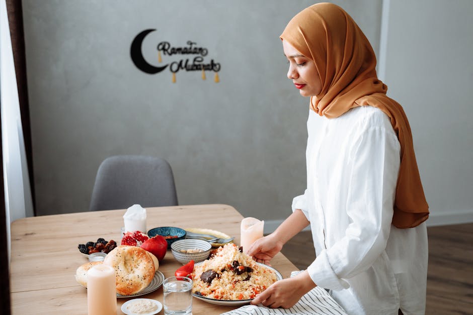 Muslim woman in hijab setting table with traditional iftar food during Ramadan.