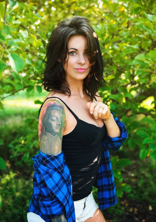 Woman in Black Tank Top and Plaid Shirt Standing Near Trees